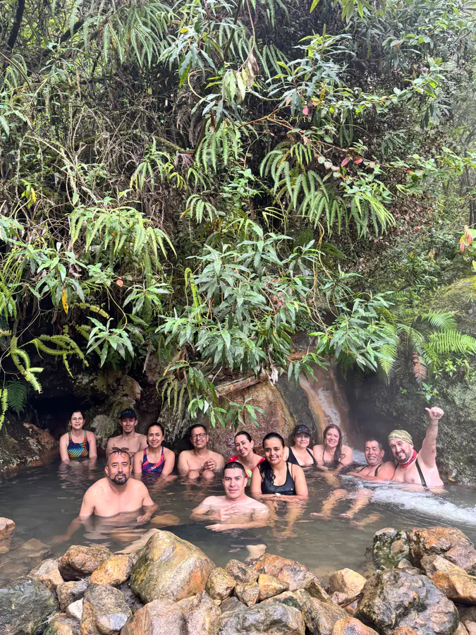 Grupo relajado y sonriente en aguas termales rodeadas de selva