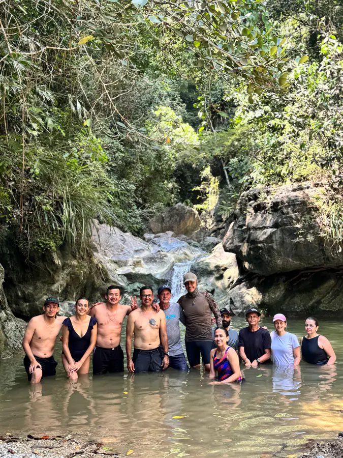 Grupo sonriente de pie en un pozo natural dentro del bosque